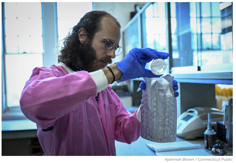 Someone working in a lab, pouring liquid into a container